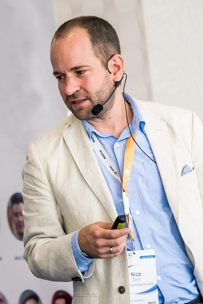 Nico Zorn giving a talk with a headset microphone and presenter in hand
